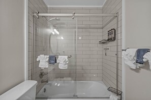 A modern bathroom with a glass-enclosed shower, a bathtub, and a towel rack with multiple towels.
