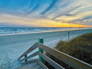 A beach with a wooden walkway leading to the shore.