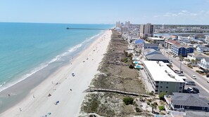 A coastal town with a beach, a pier, and buildings along the shore.