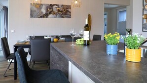 A modern kitchen with a central island, pendant lighting, and a wine bottle. - Coastal Comfort With Terrace (Ribnitz-Damgarten)