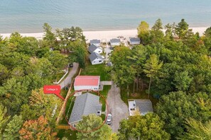 Luchtbeeld van een kustbezit met meerdere huisjes, een gebouw met een rood dak en een strand op de achtergrond.