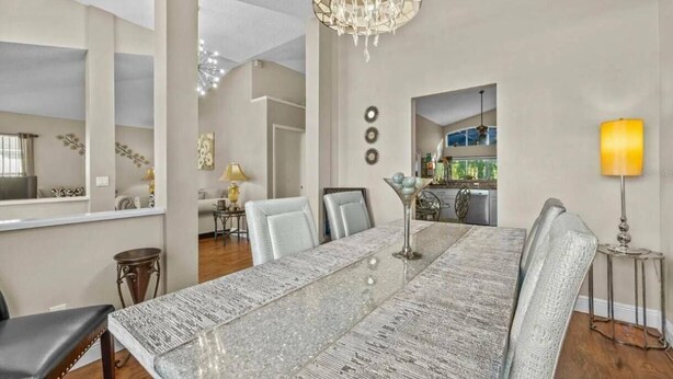 A spacious dining area with a long table, chairs, and a chandelier.