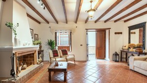A spacious living room with a fireplace, wooden beams, a large window, and a door leading outside. - Home2Book La Casita del Muelle (Garachico)