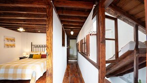 A narrow hallway with wooden beams and a bed with a checkered bedspread. - Home2Book La Casita del Muelle (Garachico)