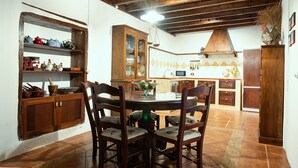 A rustic kitchen with wooden cabinets, a dining table with chairs, and a tiled floor. - Home2Book La Casita del Muelle (Garachico)