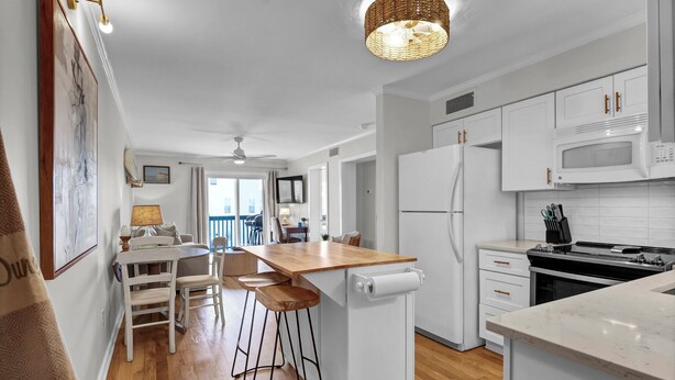 A modern kitchen with white cabinets, a wooden countertop, and a built-in oven. - Carolina Beach Retreat | Pool, Ocean View, Beach Access & Stylish Decor (Carolina Beach)