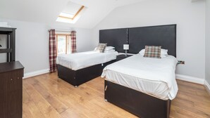 A bedroom with two beds, a skylight, and a wooden floor. - 2 Bedroom Apartrment (Newcastle-upon-Tyne)