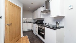 A modern kitchen with white cabinets, a black countertop, and stainless steel appliances. - 2 Bedroom Apartrment (Newcastle-upon-Tyne)
