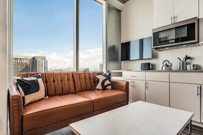 A modern kitchen with a built-in microwave, a dining area with a white table, and a leather sofa with cushions. - Boulevard Stays Downtown Highrise STU Sky Pool, Parking, Gym 15 (Phoenix)
