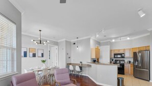 Una cocina moderna con electrodomésticos de acero inoxidable, un comedor con mesa y sillas, y una sala de estar con sofá y una mesa de centro.