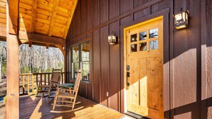 A wooden cabin with a porch, rocking chair, and a door with windows.