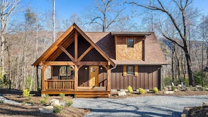 A cabin with a wooden exterior, a porch, and a small deck.