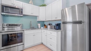 A modern kitchen with stainless steel appliances, white cabinetry, and a herringbone floor pattern.