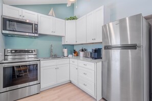 A modern kitchen with stainless steel appliances, white cabinetry, and a herringbone floor pattern.