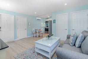 Ein modernes Wohnzimmer mit einem grauen Sofa, einem weiĂen Couchtisch und einem Essbereich mit Tisch und StĂŒhlen.
