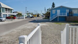 A residential street with houses, a white fence, and a clear sky.