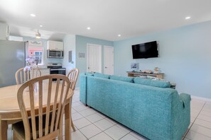 Un espacio habitable compacto con kitchenette, comedor y zona de estar con sofá.