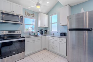A modern kitchen with stainless steel appliances, white cabinetry, and a ceiling fan.