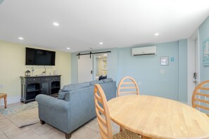 Ein modernes Wohnzimmer mit grauem Sofa, Esstisch aus Holz und Stühlen.