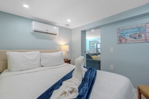 A hotel room with a bed, a wall-mounted air conditioner, a lamp, and a beach-themed wall decoration. - 🌊Walk to Beach-Pet Friendly-Cozy 1 Bedroom-Island Paradise 5🌊 (Fort Myers Beach)