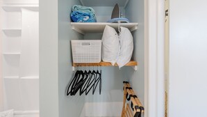 A closet with shelves, a hanging rack, and a wooden bench.