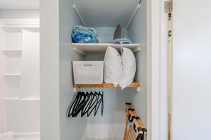 A closet with shelves, a hanging rack, and a wooden bench.
