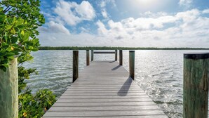 A wooden pier extending into calm water, surrounded by greenery.