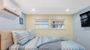 Un dormitorio con cama, ventana y aire acondicionado.