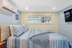 A bedroom with a bed, a window, and an air conditioning unit.