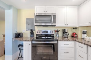 A modern kitchen with white cabinets, a built-in microwave, a stove, and a toaster.