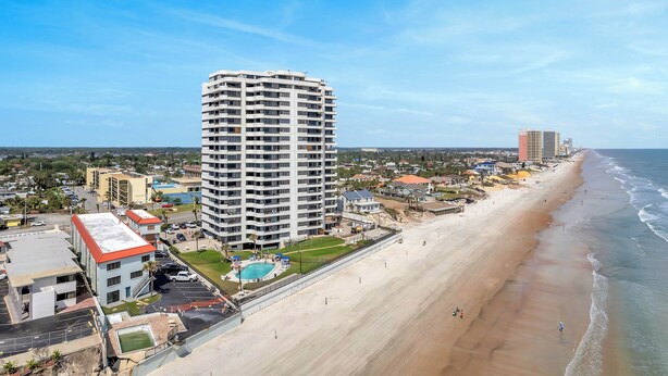 A beachfront hotel with multiple floors, a swimming pool, and a beach view.