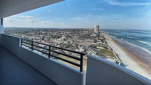 A balcony with a view of a beach and cityscape.