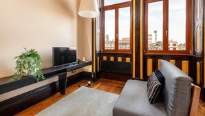 A room with a television, a plant, a sofa, and a window with a view of buildings. - Studio Near Ribeira do Porto (Porto)