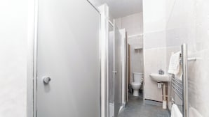 Une petite salle de bain comprenant une douche, des toilettes et un lavabo.