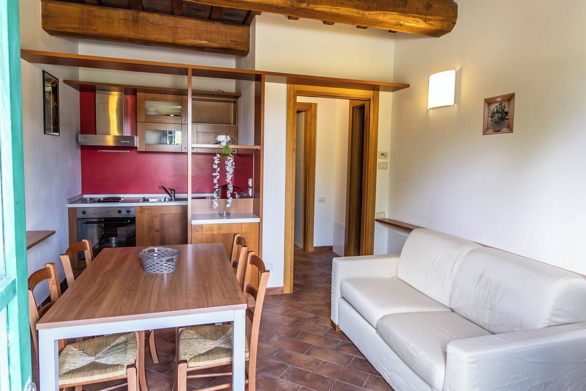 Eine moderne Küche mit Holzausstattung, einem Esstisch mit Stühlen und einem weißen Sofa im Wohnbereich.