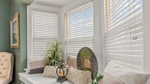 Un coin salon confortable avec un banc rembourré, une plante en pot et des objets décoratifs.