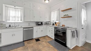 Une cuisine moderne avec des meubles blancs, un lave-vaisselle, une cuisinière et un four à micro-ondes.