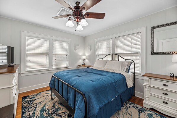 A bedroom with a bed, bedside tables, a ceiling fan, and a large mirror.