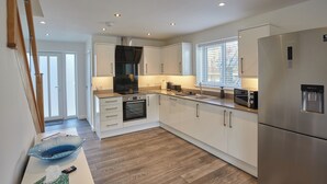 Una cocina moderna con gabinetes blancos, un refrigerador de acero inoxidable y un horno empotrado.
