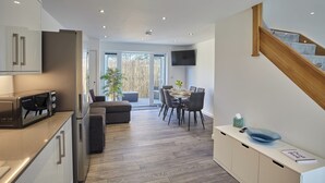 Una cocina moderna con microondas integrado, un comedor con mesa y sillas, y una escalera que lleva a otro nivel.