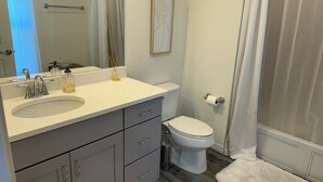 Une salle de bain avec un lavabo blanc, des toilettes et une douche.