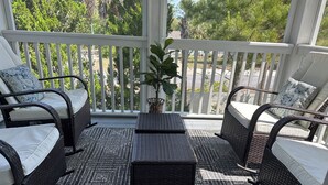 Un balcon agrémenté de meubles en osier, d’une petite table et d’une plante en pot.