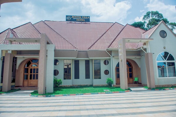 A hotel with a tiled roof, large windows, and a sign reading "ROSTEL VILLA HOTEL".