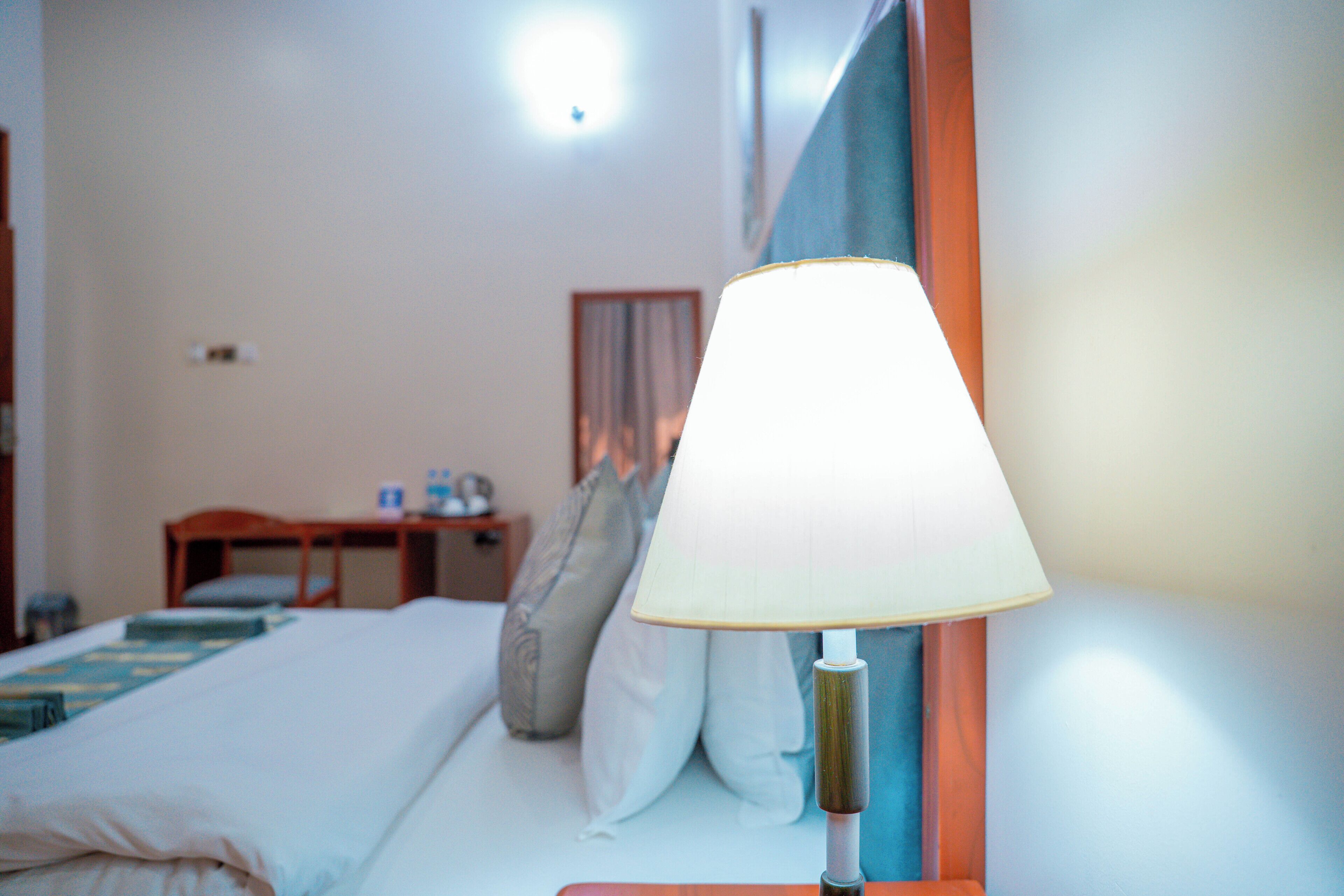 Ett hotellrum med en säng, ett sängbord, en lampa och ett litet bord.