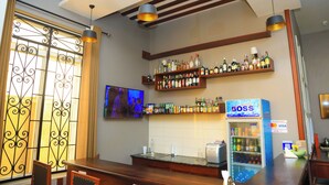A bar area with shelves of liquor bottles, a TV mounted on the wall, and a 'BOSS' branded refrigerator. - Rostel Villa Hotel (Mbeya)