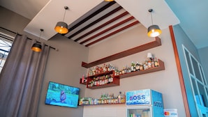 A bar area with shelves of liquor bottles, a television, and a 'BOSS' branded refrigerator. - Rostel Villa Hotel (Mbeya)