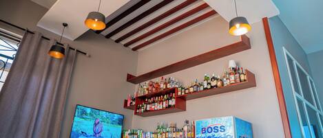 A bar area with shelves of liquor bottles, a television, and a 'BOSS' branded refrigerator.