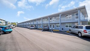 Un motel de varios pisos, con estacionamiento y cielo despejado.