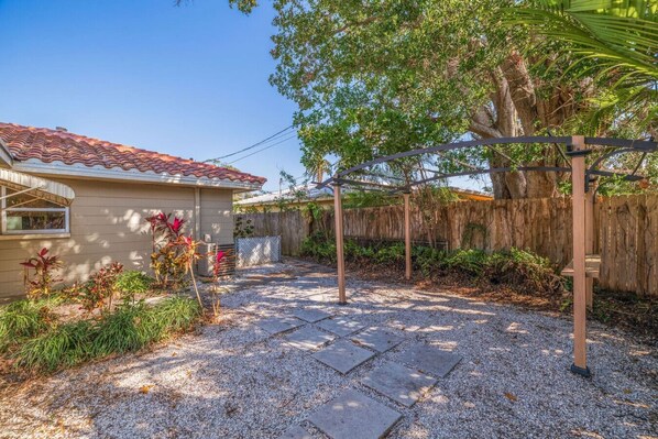 Un patio trasero residencial con un porche, un pérgola y una valla de madera.