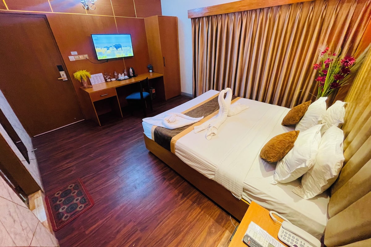 Ein Hotelzimmer mit Bett, Schreibtisch, Fernseher und Vorhang.
